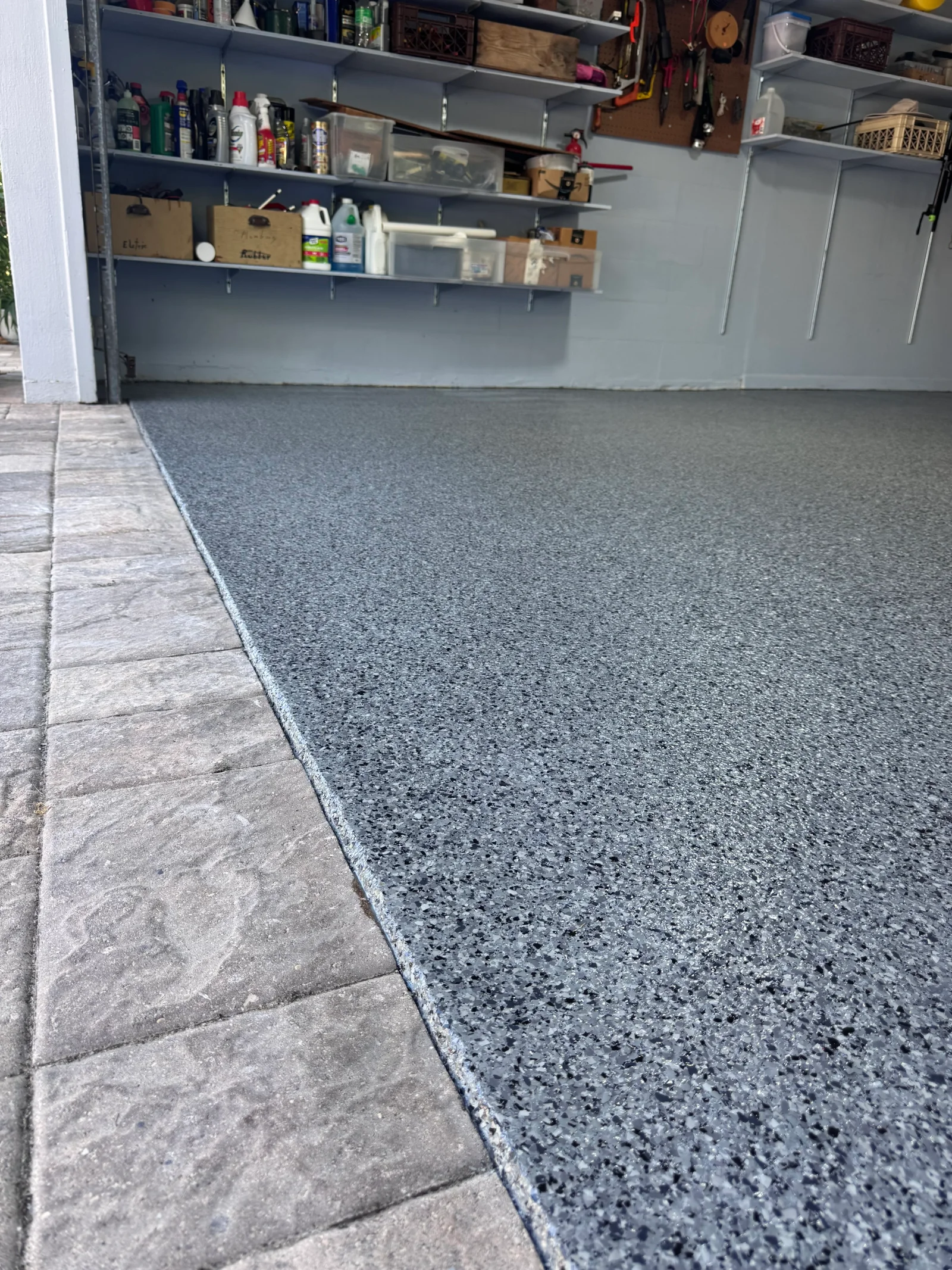 Speckled gray epoxy-coated garage floor with clean edge transition to tile entryway