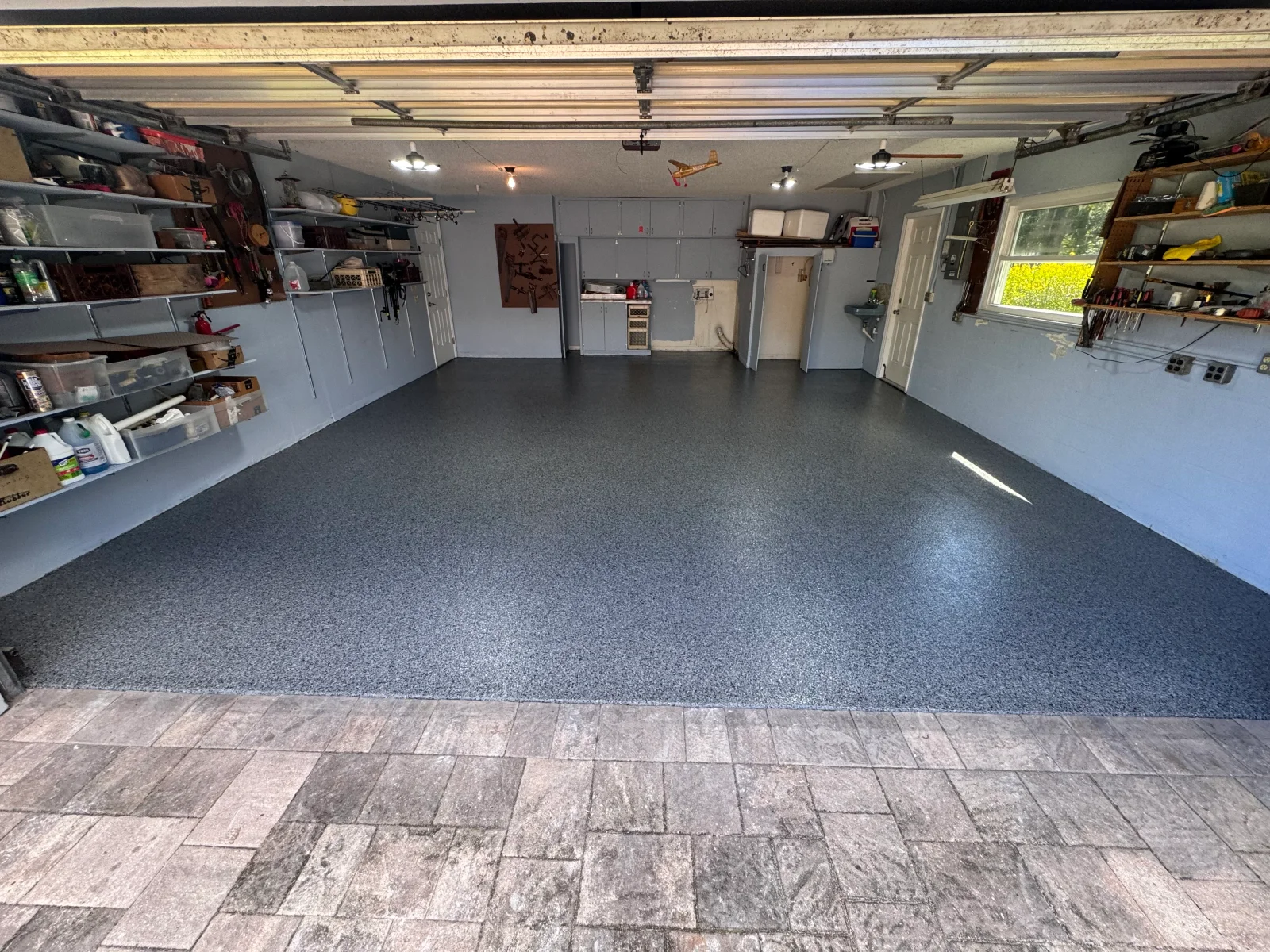 Gray epoxy-coated garage floor with organized wall storage and shelving
