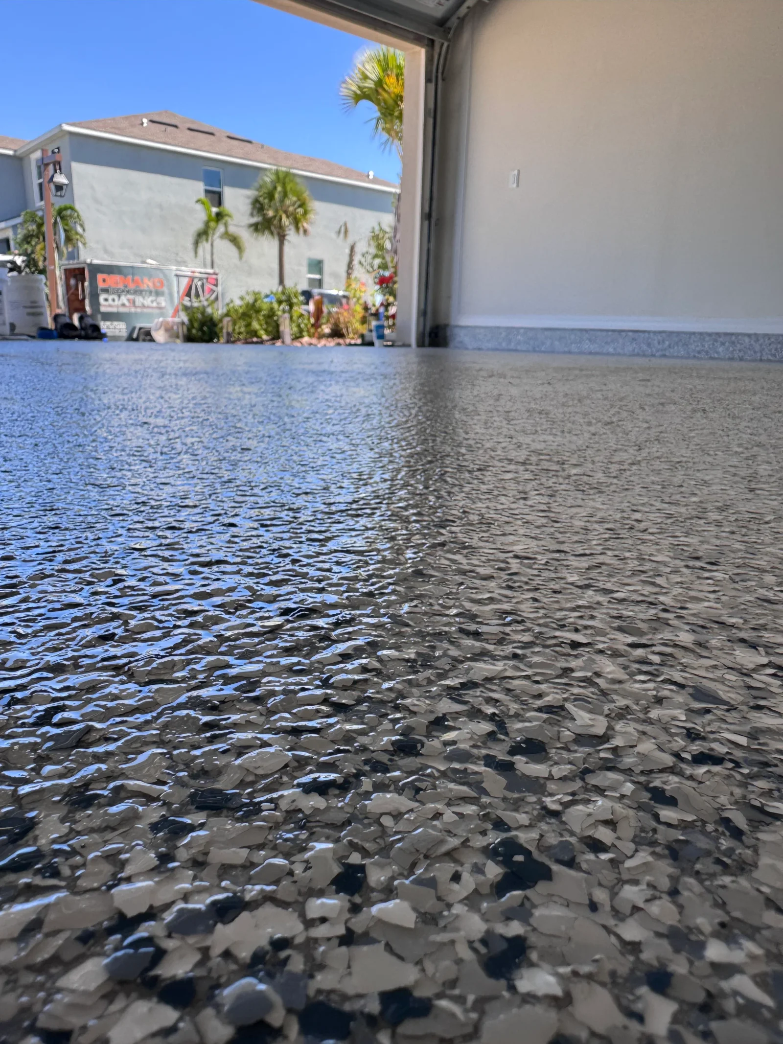 Speckled gray and black epoxy-coated garage floor with glossy finish and aggregate texture
