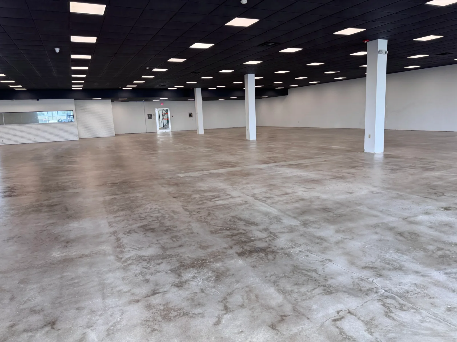 Polished concrete floor in commercial warehouse with LED lighting and support columns